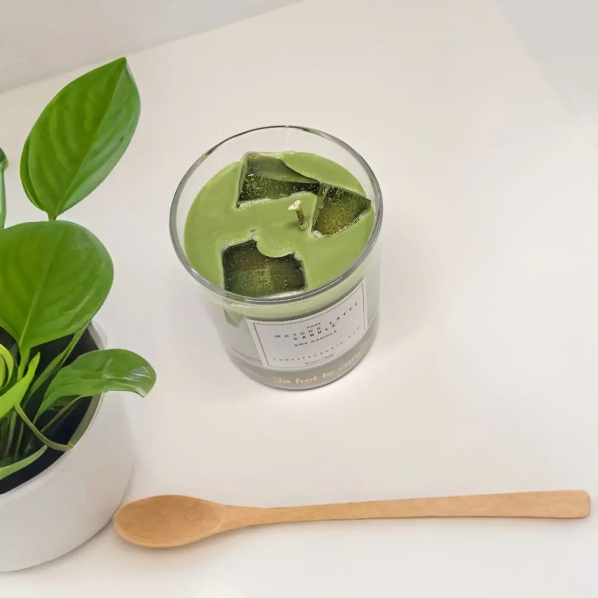 Matcha kaars in glas met houten lepel en groen blad