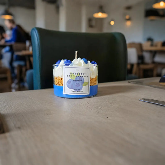 Geurkaars met blauwe bessen op cafétafel met mensen op de achtergrond.