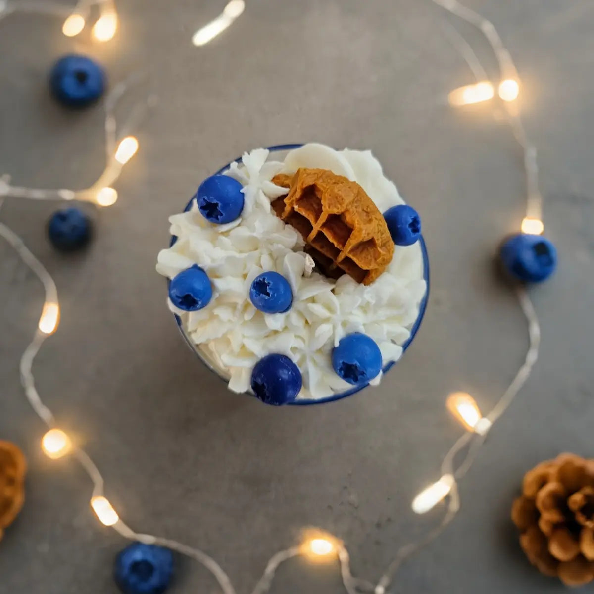 Bovenaanzicht van sojakaars in dessertstijl met lichtsnoer en blauwe bessen