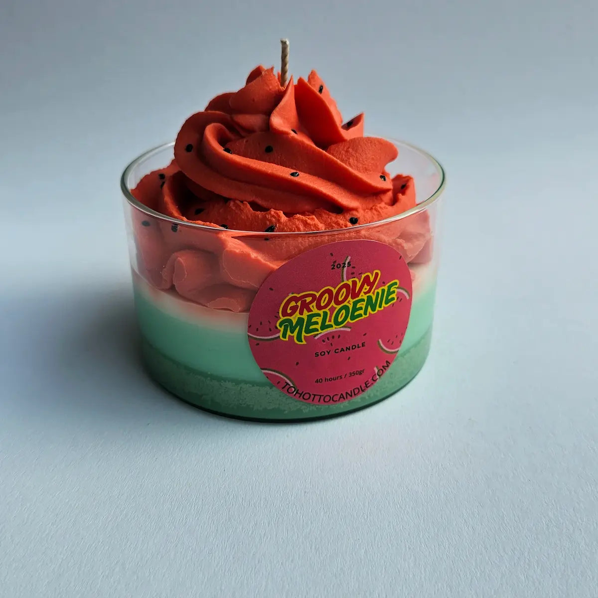 Close-up van de roze watermeloenkaars tegen blauwe achtergrond met decoratieve pitjes.
