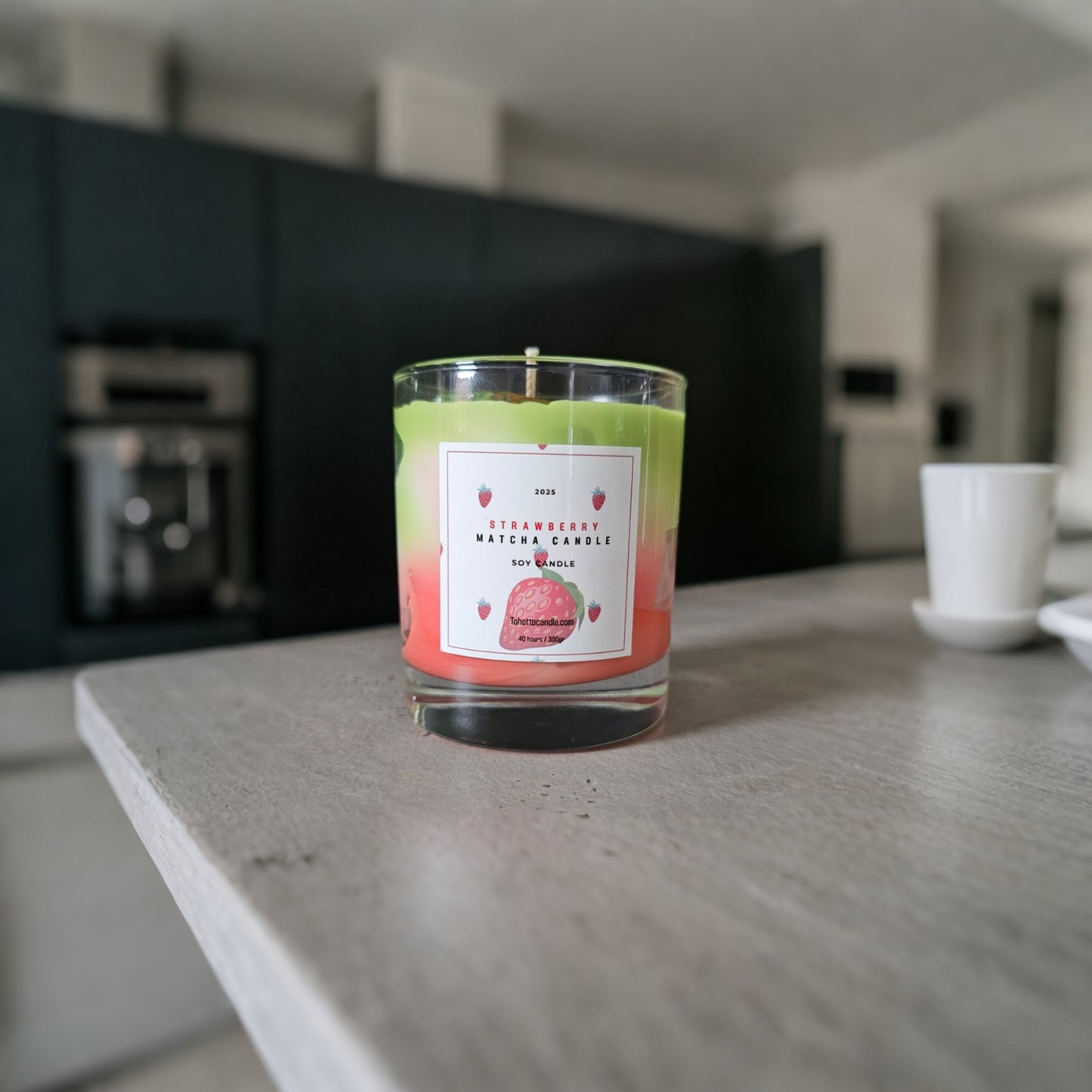 Groene en roze geurkaars op lichte houten tafel in een minimalistische keuken.