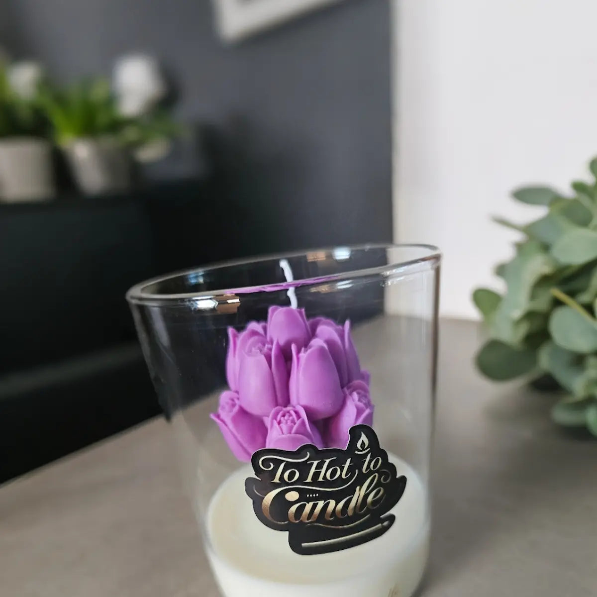 Paarse bloemkaars in glas met label sfeervol op tafel met kamerplant
