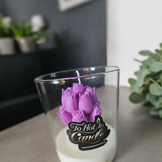 Paarse bloemkaars in glas met label sfeervol op tafel met kamerplant