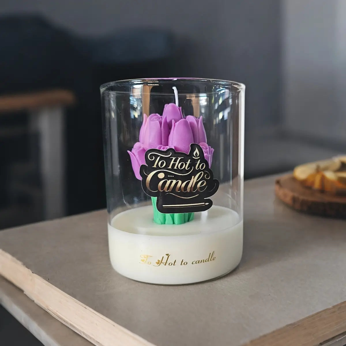 Paarse bloemkaars in glas, geplaatst op houten plank als eyecatcher