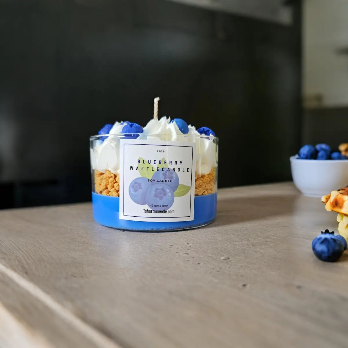 Blauwe geurkaars met blauwe bessen decoratie en naturel houten achtergrond.