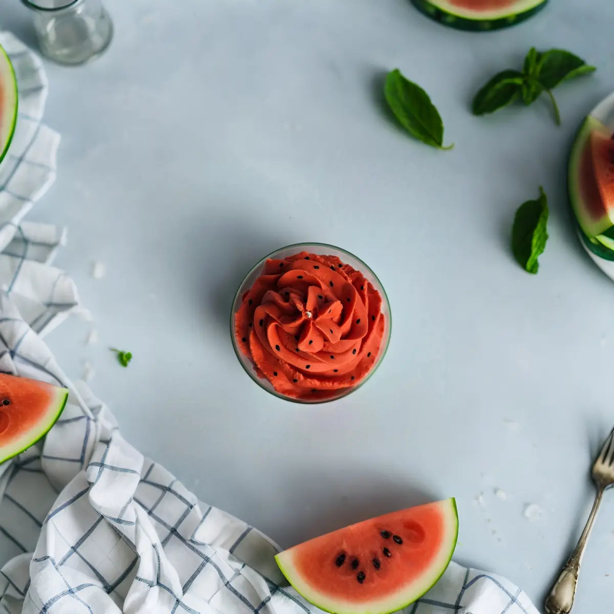 Creatieve flatlay van Groovy Meloenie kaars met ijsblokjes, munt en watermeloenpartjes.