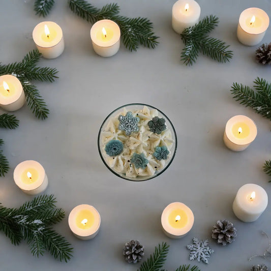 Bovenaanzicht van Winter Glow geurkaars sfeervol verlichte kaarsen in een ronde opstelling met dennentakken en winterlicht